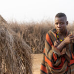 Sunrise and a young Nyangatom man stands with his tooth brush fashioned out of green sapling branches (image by Inger Vandyke)