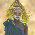A young Suri girl with her decoration of berries in the early morning sun (image by Inger Vandyke)