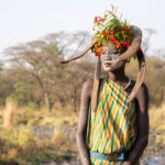 A beautiful Suri girl with her decoration of seed pods and flowers (image by Inger Vandyke)