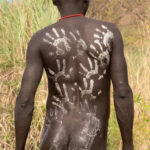 To prepare for battle, young Suri men use their hands and fingers to paint their bodies with chalk (image by Inger Vandyke)