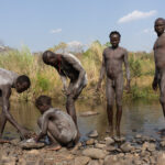 A group of Suri men paint their bodies before they go into battle (image by Inger Vandyke)