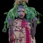 A young Suri girl decorated with a plant she had pulled from the fields around her village (image by Inger Vandyke)