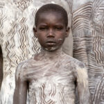 A young boy painted to become a Suri warrior (image by Inger Vandyke)