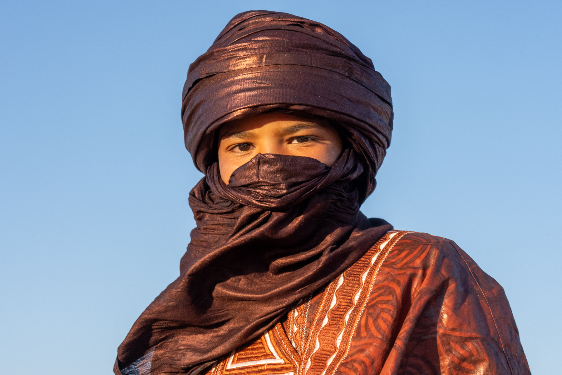 Young Tuareg boy waiting to watch the camel dancing in the desert (image by Inger Vandyke)