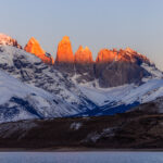 Sunrise hits the top of Patagonia's iconic Torres del Paine mountains, giving the tips of the towers the appearance of candles (image by Virginia Wilde)