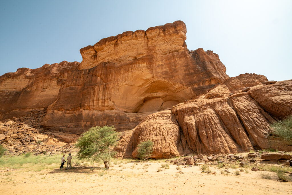 Two of our guests look up to the stunning Ennedi rock art site of Archei (image by Inger Vandyke)