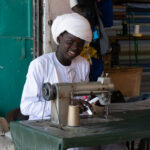 A young boy makes and mends clothes in the streets of Kalait (image by Inger Vandyke)