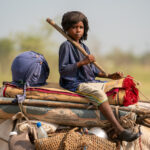 A Wodaabe boy sits atop his deconstructed home on a cow while he rides with 'migrating' Wodaabe families (image by Inger Vandyke)