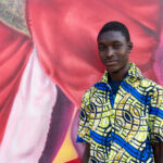 A young Beninese man wearing a stunning wax cloth shirt at the street art gallery of Cotonou (image by Inger Vandyke)