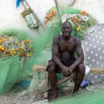 A friendly West African fisherman sitting amongst his nets at Cape Coast (image by Inger Vandyke)