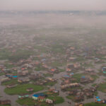 Ganvie in the mist and fog of a harmattan. The distant city of Cotonou is on the horizon (image by Inger Vandyke)
