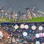 Split worlds - the daily fish market on one side of the fence and moored pirogues on the other (image by Inger Vandyke)
