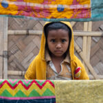 A young son of a brick worker looks at me through the washing (image by Inger Vandyke)