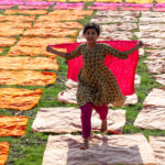 Young girl running with a newly dyed piece of fabric before she lays it out to dry in the sun (image by Inger Vandyke)