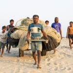 A group of fishermen deliver trailers full of repaired nets to boats moored off the beach at Chittagong (image by Inger Vandyke)