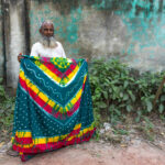 A fabric dying worker proudly shows off his work (image by Inger Vandyke)