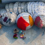 Women preparing dinner alongside a chicken with her babies and drying washing on rice topas (image by Inger Vandyke)
