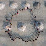 A ring of children hold hands in a circle at a rice drying courtyard (image by Inger Vandyke)
