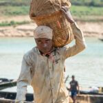 Sand miner carrying loads to the riverbank (image by Inger Vandyke)