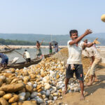 A stone worker tosses a rock into a nearby truck (image by Inger Vandyke)
