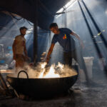 Young men toil over steaming, cooking yoghurt (image by Inger Vandyke)