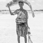 A Diyes woman transporting a fish and a giant Nile Perch back to her home (image by Inger Vandyke)