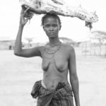 A Diyes woman carrying the gigantic skull of a Nile Crocodile on her head (image by Inger Vandyke)