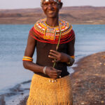 A smiling El Molo woman wearing her trademark grass skirts at sunset on Lake Turkana (image by Inger Vandyke)