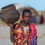 A young Gabra man takes traditional gourds out to milk camels (image by Inger Vandyke)