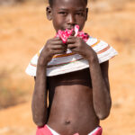 A young Rendile girl holding Desert Rose flowers (image by Inger Vandyke)