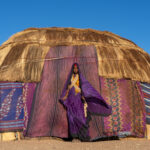 A young Gabra bride stands in the doorway of her newly built Mandasse. She is wearing an Agogo, or cream coloured cloth, that new Gabra brides wear for the first four months they are married (image by Inger Vandyke)