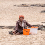 A fisherwoman with her box of treats and bucket of fish at Tombua (image by Inger Vandyke)