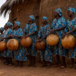 Otamari women playing large tamtam drums fashioned out of gourds in front of a traditional tata (image by Ingrid Koedood)