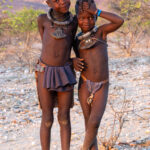 Young Ovahimba girls smiling at sunset in the mountains of southern Angola (image by Inger Vandyke)
