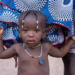 A beautiful Ovakuvale baby holding the wax cloth skirt of her mother (image by Inger Vandyke)