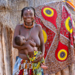 A beautiful Ovangambwe woman and her baby outside her home (image by Inger Vandyke)