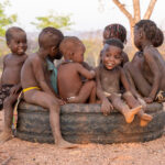 A group of young Ovatwa children playing on a large tyre (image by Inger Vandyke)