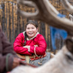 A young Tsaatan lady smiling with her reindeer (image by Inger Vandyke)