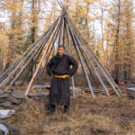 A Tsaatan man stands outside the framework of his newly constructed Tepee tent (image by Inger Vandyke)