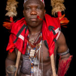 Portrait of a Kossou or kpohinto (Voodoo shaman). A shaman serves as a spiritual guide or mediator between the physical and spiritual worlds. The red feathers and adornments show his devotion to the deity of Heviosso (image by Ingrid Koedood)