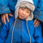 Safe in his father's arms, a young Tsaatan boy pouts when posing for photos (image by Inger Vandyke)