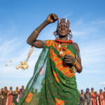 A beautifully decorated Jie woman singing at a ceremony (image by Inger Vandyke)