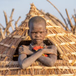 A young Jie boy sits at the entrance of an Ekero (granary) (image by Inger Vandyke)
