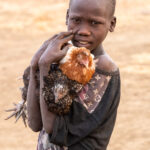 A young Jie boy with his chicken (image by Inger Vandyke)