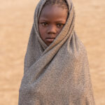 A Jie child wrapped up to stay warm at sunrise (image by Inger Vandyke)