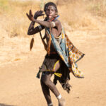 An athletic Jie woman arrives dancing at a ceremony (image by Inger Vandyke)