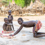 Young Laarim girls at their village grain grinding pit (image by Inger Vandyke)