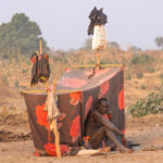 Mundari man contemplating the day outside his sleeping tent (image by Inger Vandyke)