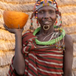 A beautiful Toposa woman walking through her village with a gourd filled with goat's milk (image by Inger Vandyke)
