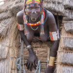 A Toposa woman climbing out of her Ekore (stilted granary) (image by Inger Vandyke)